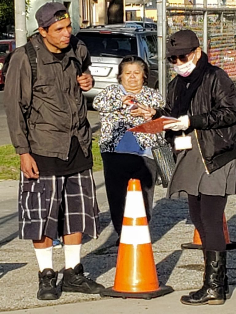 Neighborhood residents stand in line to receive a grab and go dinner